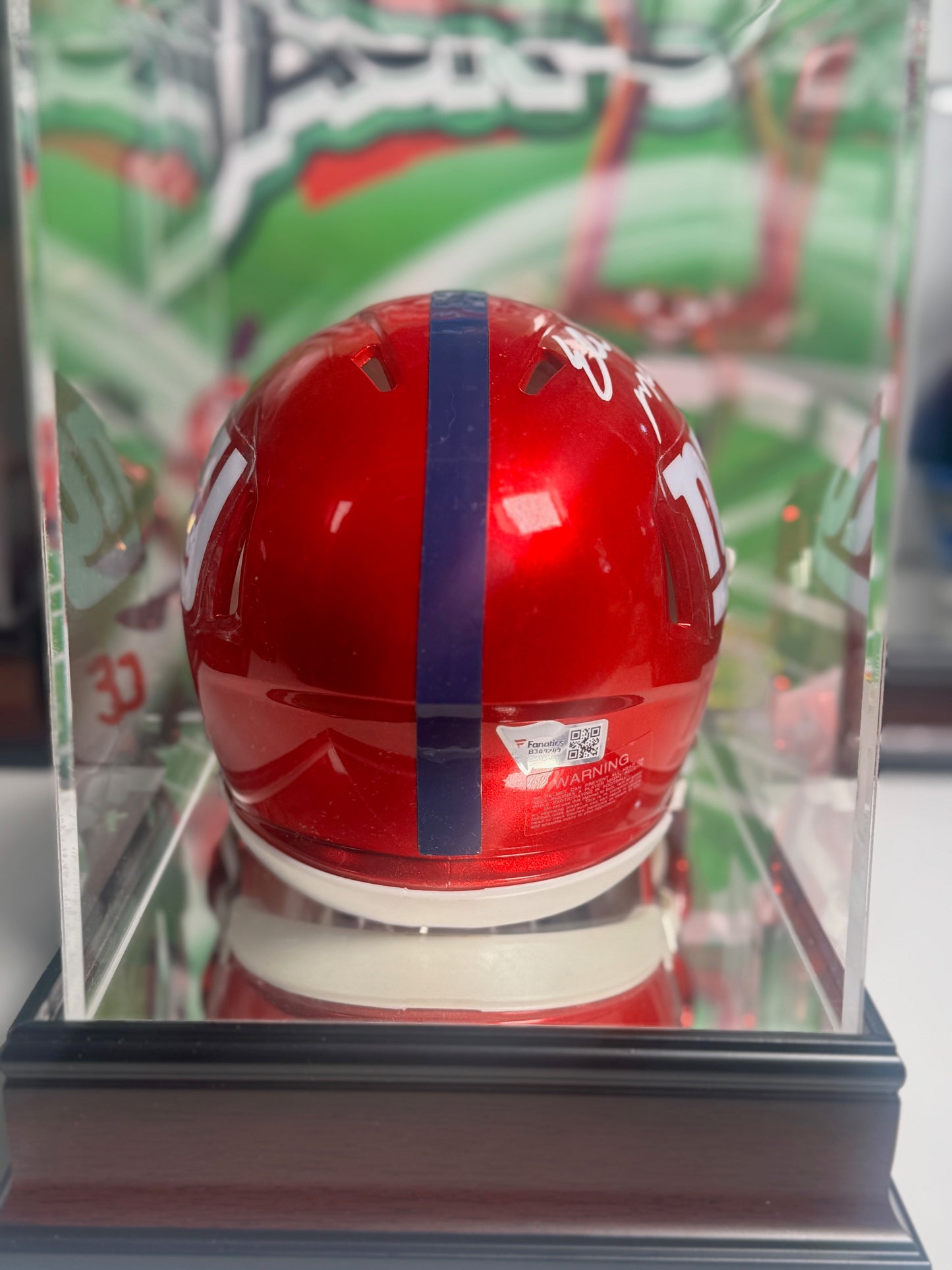 Side view of Eli Manning signed mini helmet with bright red shell and blue stripe